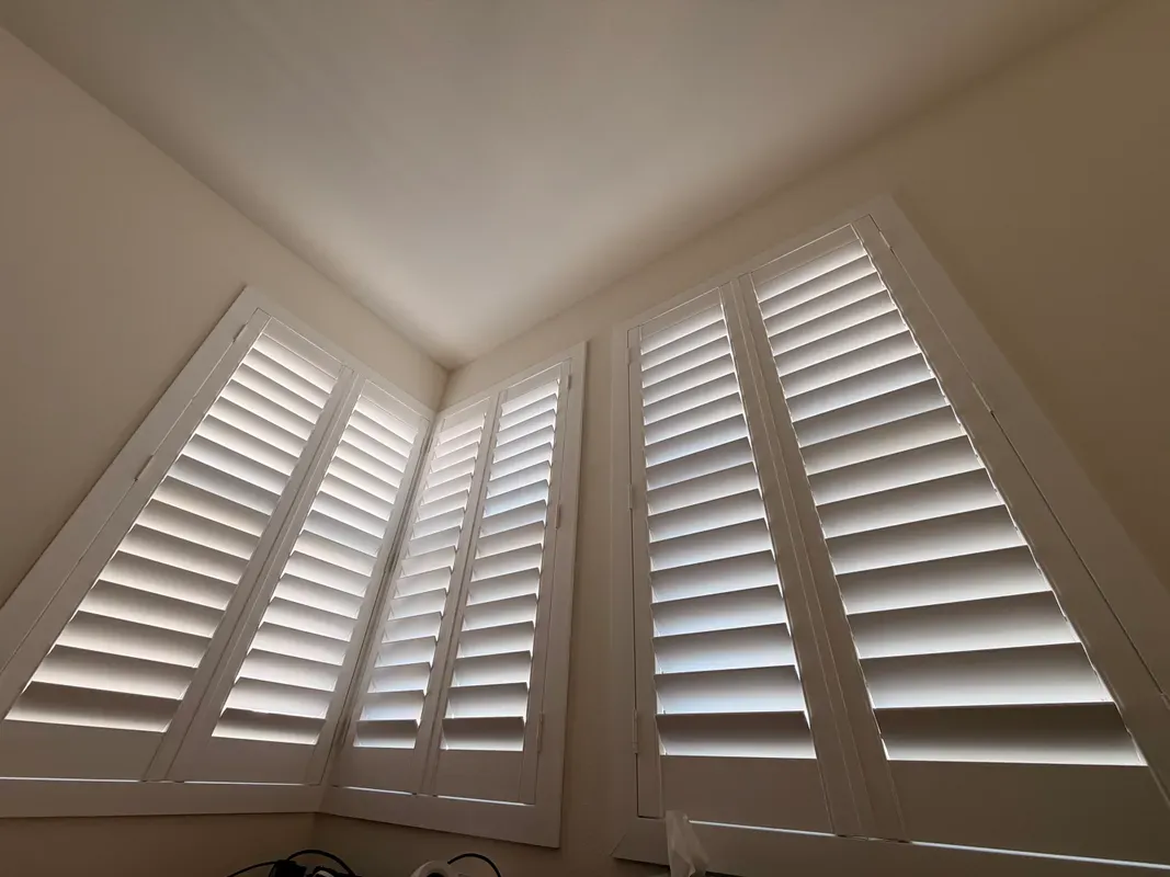 White plantation shutters on a vaulted corner window